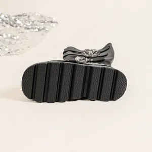 Vue détaillée de la semelle épaisse et des boucles métalliques décoratives des bottes noires
