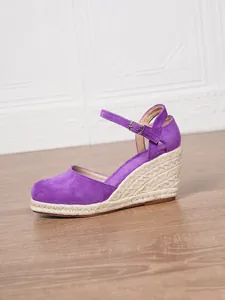 Dettaglio di sandalo con zeppa in pelle scamosciata viola e suola in corda intrecciata