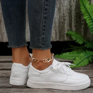 Nahaufnahme weißer flacher Schnürsneaker an einem Modell mit blauen Jeanshosen.