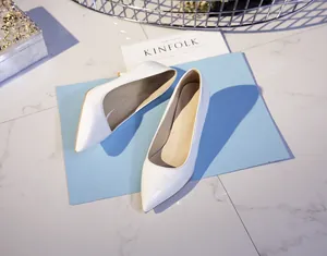 Top-down view of elegant white pointed-toe high heels on a blue card and marble background