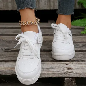 Detailansicht der weißen Freizeit-Sneaker zum Schnüren und des groben Fußkettchens