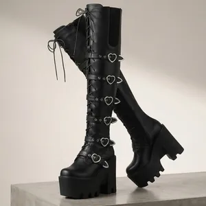 Vue détaillée de bottes compensées noires avec boucles en cœur métalliques et lacets