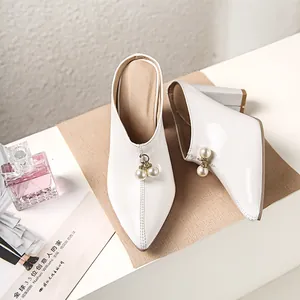 Elegant white pointed-toe block heel mules featuring a stylish pearl bead charm.