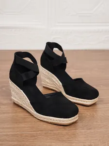 Vista lateral de sandalias de cuña en ante negro con suela de esparto y elásticos