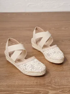 Detalle de alpargatas de cuña beige con bordado floral y correas cruzadas