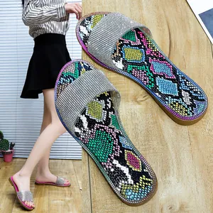 Detail van platte sandalen met kleurrijke slangenprint en strass-bandje