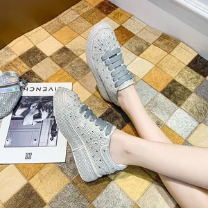 Close-up of women's sparkling rhinestone platform sneakers with grey laces on carpet.