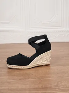 Elegantes sandalias de cuña en ante negro con suela de esparto y tiras elásticas.
