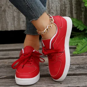 Detailansicht roter Schnür-Sneaker für Damen mit weißer dicker Sohle und Pflanzenhintergrund