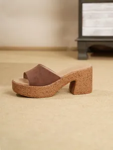 Primer plano de sandalia de plataforma en ante marrón con tacón de textura de corcho.