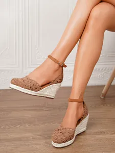 Primer plano de sandalias de cuña de encaje marrón con tira al tobillo para mujer.