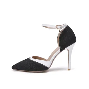 Close-up of black denim and white pointed-toe high heels with an ankle strap.
