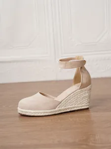 Perfil de sandalia con cuña beige, suela de esparto y tira en el tobillo