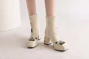 Detail of cream platform ankle boots with Halloween pumpkin print and square toe