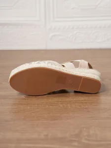 Vista inferior de sandalias de cuña tipo alpargata de lona beige con suela de goma marrón