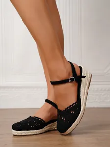 Primer plano de sandalias alpargatas de cuña de ganchillo negro con detalle de yute.