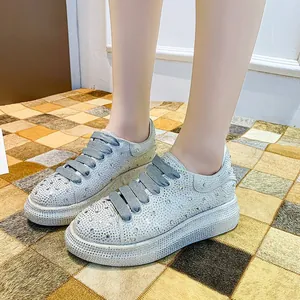 Detailed close-up view of women's silver rhinestone platform sneakers on a textured mat