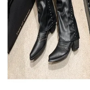 Gedetailleerd beeld van zwarte vintage western laarzen met metalen klinknagels en spitse neus