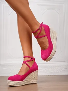 Detalle de sandalias con cuña de esparto en ante rosa con plataforma trenzada y correas