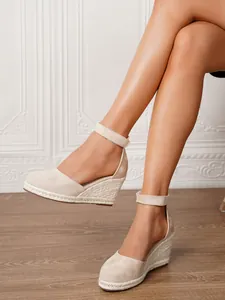 Detalle de sandalias de cuña de esparto beige para mujer con tira al tobillo
