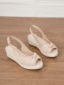 Stylish beige peep-toe wedge espadrilles featuring rope-wrapped platform and knot detail.