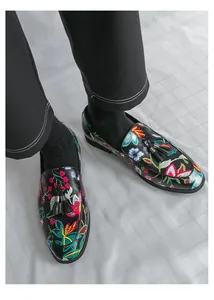 Detail view of men's black loafers featuring colorful floral embroidery and tassels.