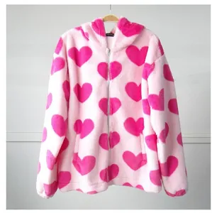 Vista dettagliata di una felpa con cappuccio in morbido peluche rosa con motivi a cuore