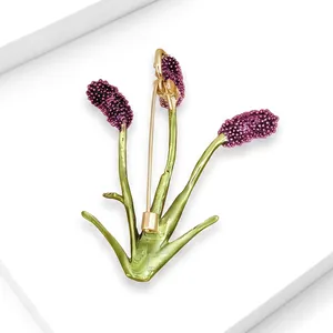 Vista detallada de un elegante broche Sanguisorba morado con tallos verdes y alfiler dorado