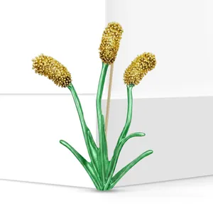 Primer plano de un elegante broche con forma de planta en verde y dorado