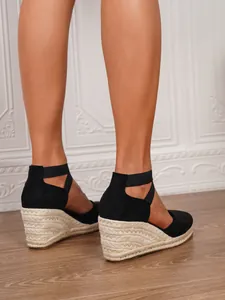 Detalle de sandalias de esparto negras con cuña y plataforma de paja tejida