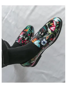 Detailed view of men's black loafers featuring colorful floral embroidery and tassels.