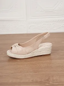 Side view of beige suede peep-toe wedge sandal with decorative knot and braided jute sole