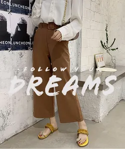 Stylish yellow ruffled flat thong sandals styled with brown trousers in a modern interior.