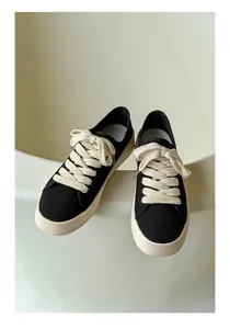 Dettaglio delle sneaker in tela nera di design con lacci spessi e stile retrò classico.