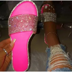 Gros plan de sandales roses vives avec des brides ornées de strass étincelants.