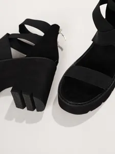 Détail du talon compensé texturé et des brides élastiques de la sandale noire à plateforme