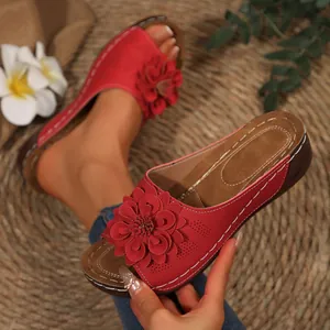 Primer plano de sandalia de cuña roja con flor 3D decorativa y costura blanca