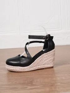 Vue latérale de sandales compensées noires à bout fermé avec semelle en jute tressée.