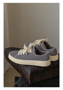 Vista laterale di sneaker in tela grigia premium con larghi lacci color beige