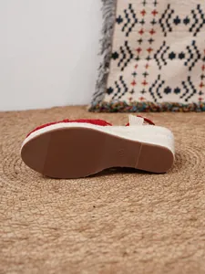 Detalle de la suela de sandalias rojas con cuña de esparto con agarre texturizado y tacón trenzado.
