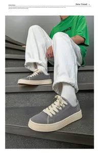 Dettaglio di sneaker in tela grigia con lacci spessi indossate da una persona su scale.