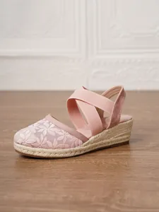 Vista detallada de sandalias de cuña rosas con encaje floral y tiras cruzadas