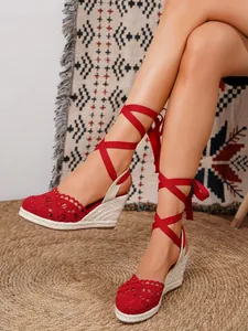 Primer plano de alpargatas de cuña con encaje rojo y cintas elegantes para anudar