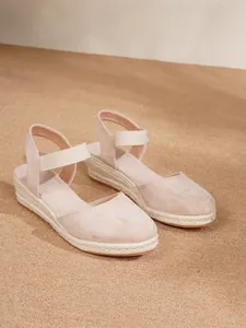 Primer plano de sandalias de cuña en gamuza rosa con suela de plataforma de yute trenzado