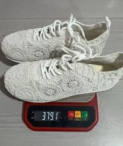 Detailed weight measurement of white lace crochet sneakers on a digital scale