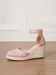Vista lateral de sandalias con cuña de ante rosa para atuendos de vacaciones de verano.