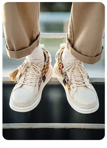 Detail view of men's woven thick-sole sneakers with colorful embroidery and rope laces.