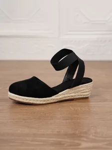 Detalle de sandalia alpargata con cuña negra, tacón de yute y correa en el tobillo
