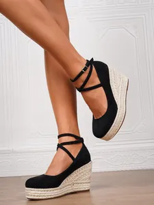Elegantes cuñas de alpargata negras con tiras al tobillo y suela trenzada.