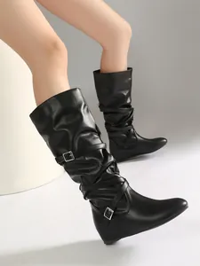 Detailed side view of black mid-calf slouchy leather boots with crossed buckle straps